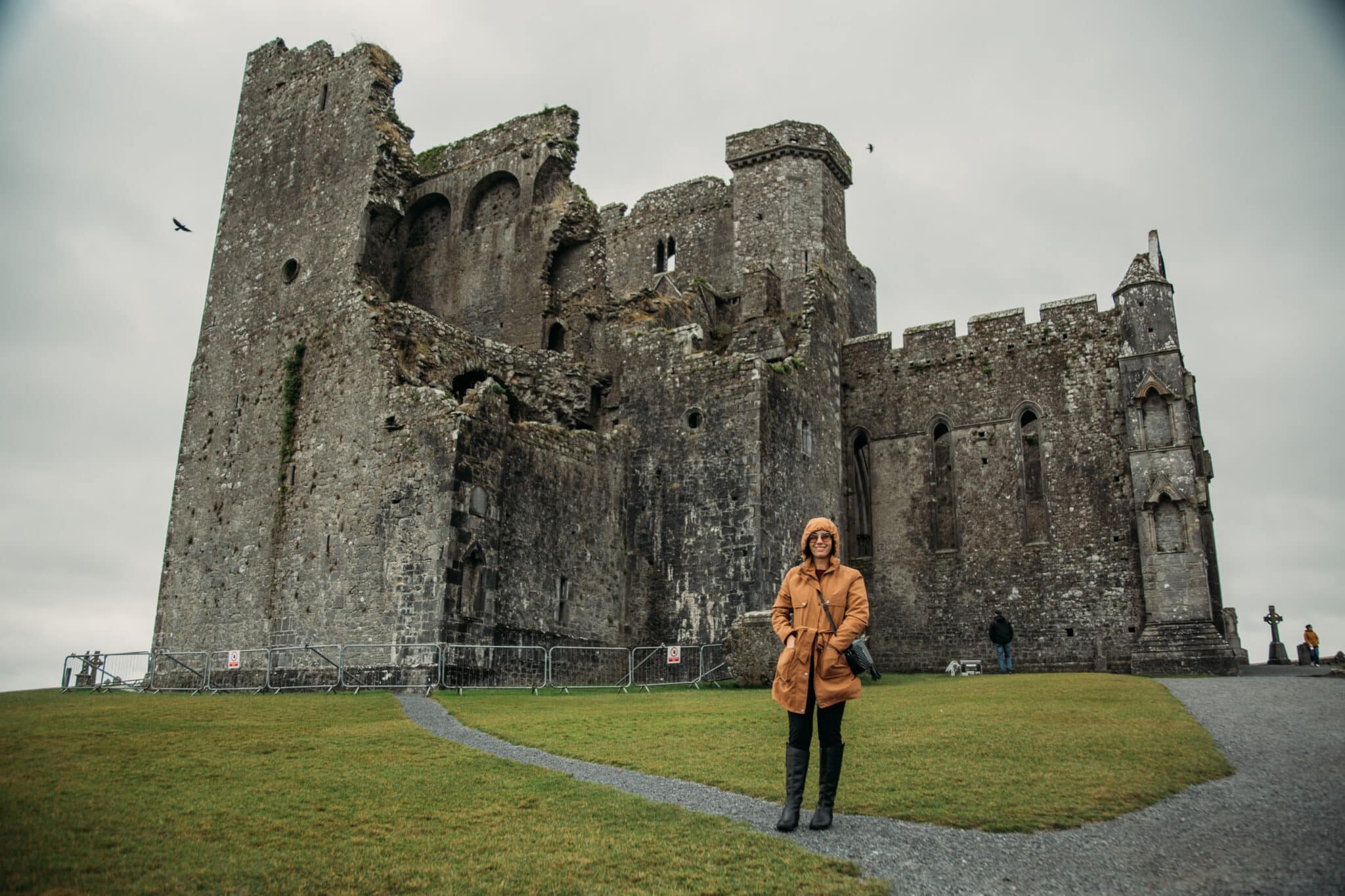 Lindsey of Have Clothes, Will Travel wearing a scottevest jacket standing in front of the Rock of Cashel in Ireland