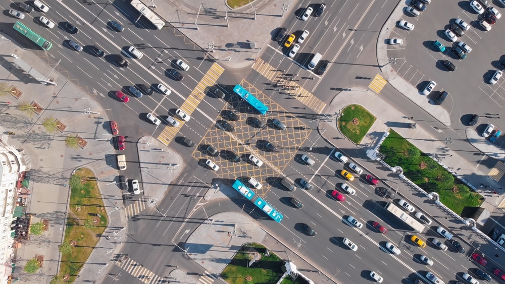 Beautiful view from above to a busy road junction in Moscow. Colorful cars and trucks driving straight forward in both directions and pedestrians crossing the road on a sunny summer day.