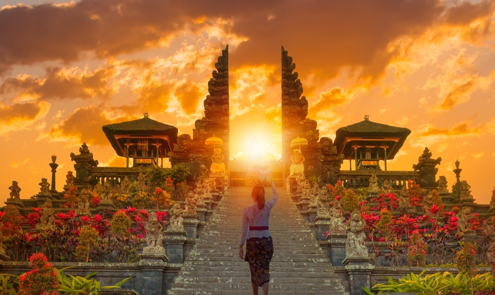 Beautiful balinese girl walking in traditional costume - Pura Besakih temple on the slopes of Mount Agung largest and holiest temple at sunset - Bali, Indonesia