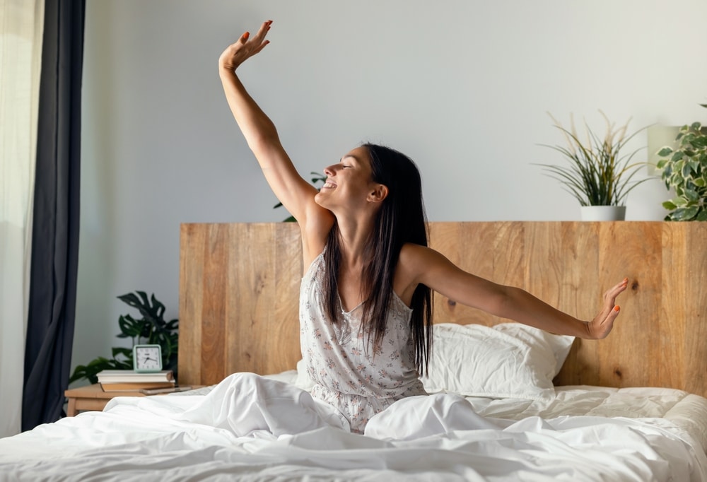 Shot of beautiful young woman stretching in the bed after wake up