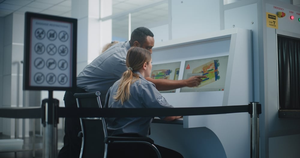 Airport Security Checkpoint: Two Diverse TSA Workers Controlling X-ray Scanning of Suitcase on Computer Monitors Using Modern Program. Advanced Baggage Screening Procedure Technology, Metal Detector.
