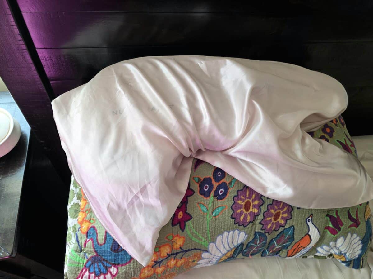 A satin pillowcase with the Nurse Jamie Beauty Bear Memory Foam Pillow stacked on top of a regular pillow