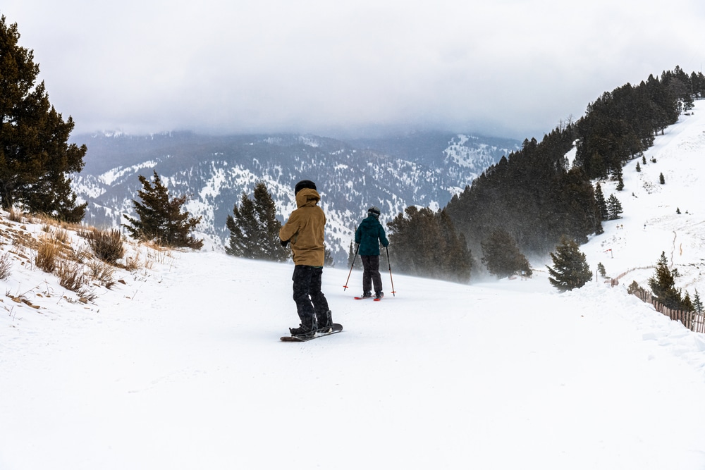 Two men snow riding from top of the mountain, Jackson Hole, Wyoming, USA. Heavy snow winter weather