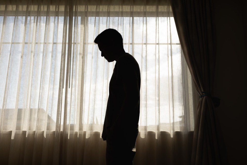 Sad man in a dark room full of desperation thoughts. Portrait of thoughtful sad man alone. Fear, sadness, abuse, depression, addiction.	