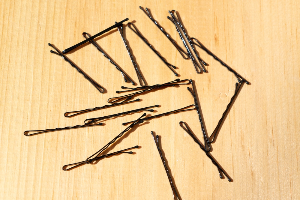 Black bobby pins on wood background