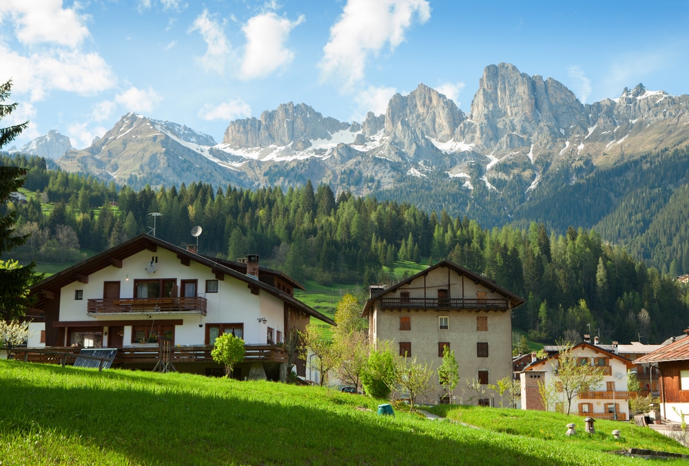 Houses are surrounded by the Dolomites, Comune di Falcade, Italy. View of a typical alpine residential structure.