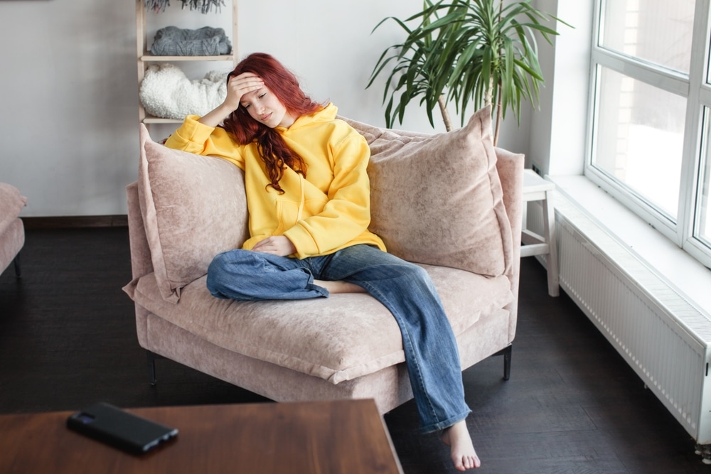 Upset,Thoughtful,Young,Woman,Sitting,On,Couch,,Looking,To,Aside