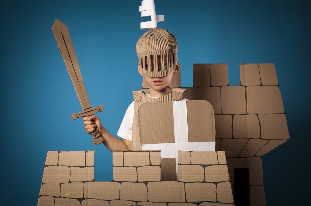photo of the child on the medieval castle decorations background made of cardboards
