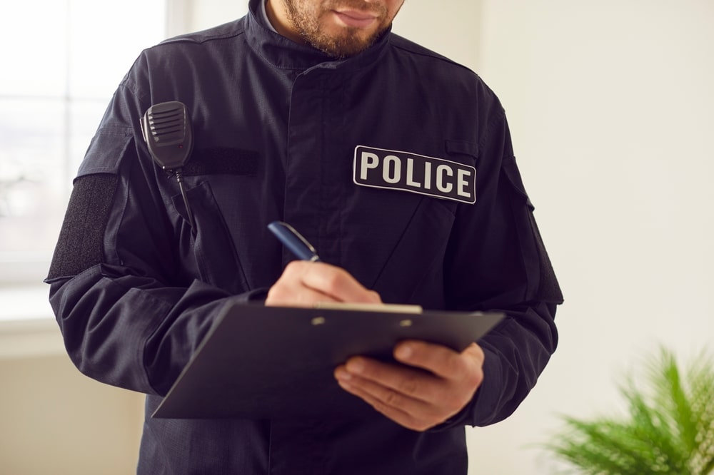 Policeman, officer police man in uniform writing crime reports form, gathering prosecution evidence close up. Emergency service worker busy filling official papers, information