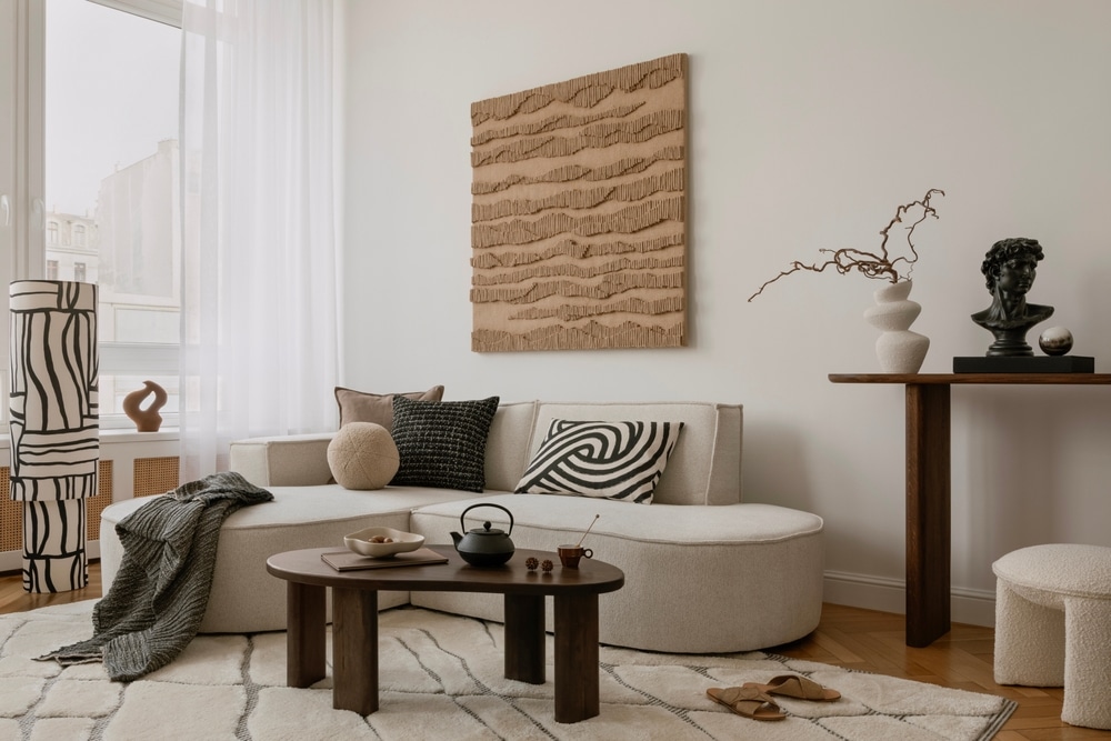 Elegant lounge space with curved sofa, abstract artwork, and a curated console arrangement in earthy hues.