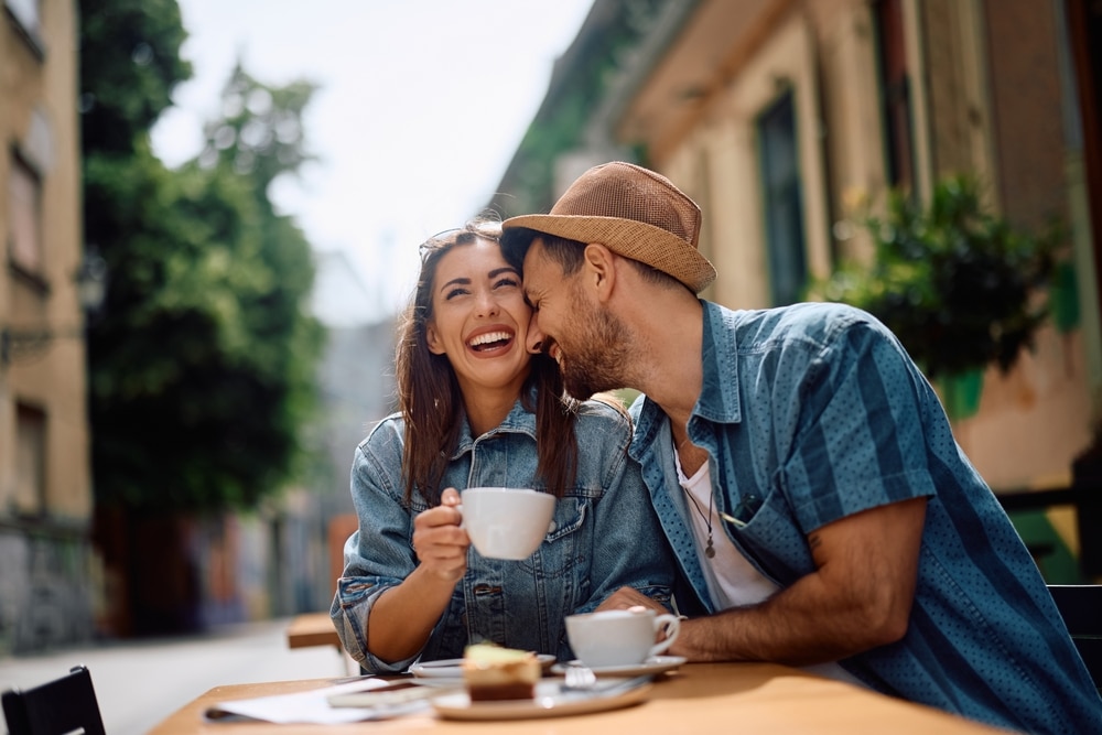 Happy couple of travelers drinking coffee in sidewalk cafe.