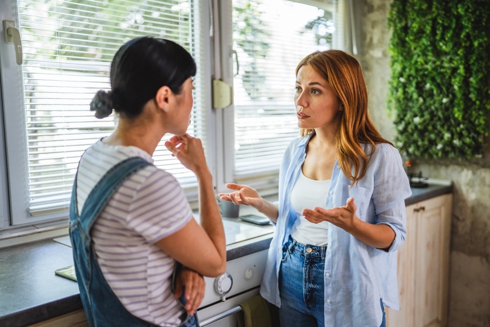 Two multicultural diverse women stand in the kitchen and arguing, heated debate