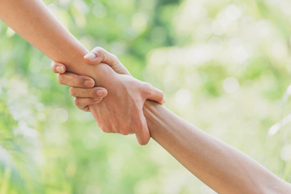 Helping hands concept. Hand holding for help on nature background.