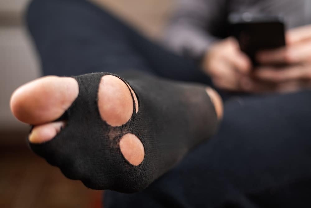 holey socks. A man sits in holey socks.