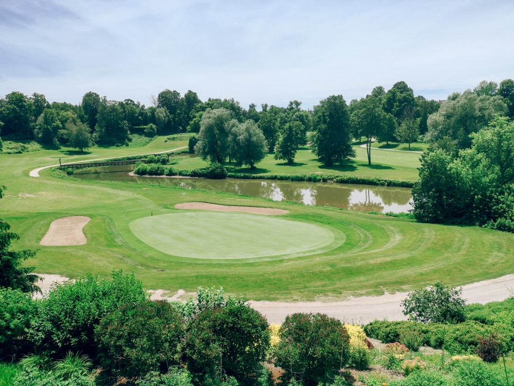 Beautiful green landscape of Canadian Ontario country-side Alliston town with golf course and small lake pond on sunny day. Serene nature scene view outdoor country village at summer.