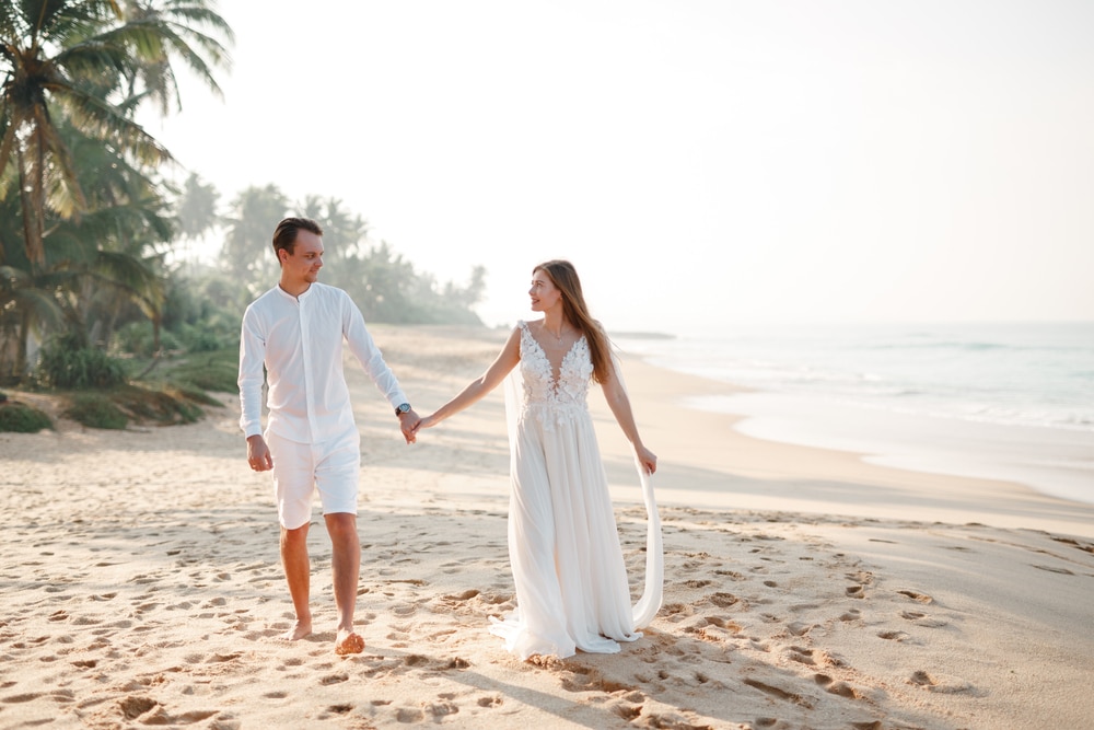 young loving happy couple on tropical beach with palm trees, wedding on beach