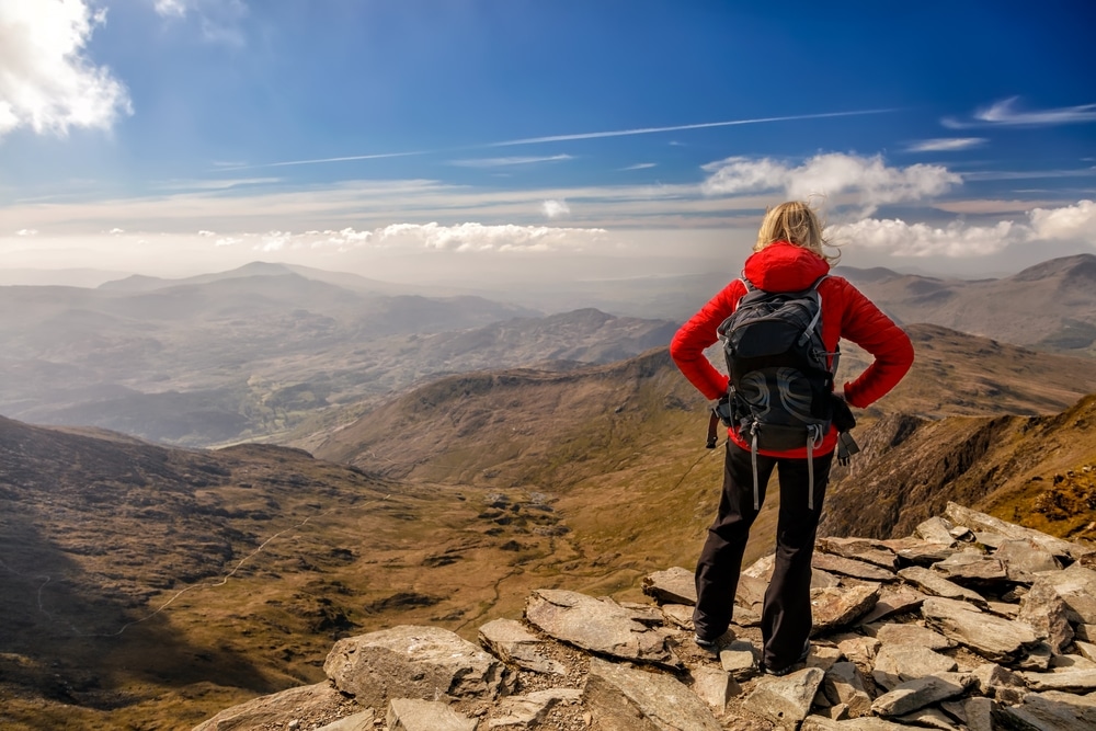 Snowdonia travel and tourism view of young Caucasian female hiker with backpack enjoying her successful adventures Wales