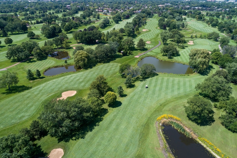 Aerial view of a suburban Chicago golf course with fairways, golf cart, ponds and sand traps.