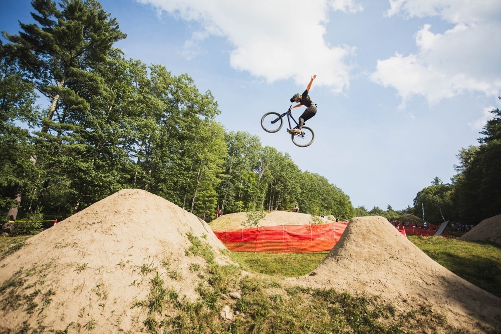 NORTHFIELD, NEW HAMPSHIRE - JULY 20, 2019: Slopestyle rider performs a tuck no-hander at Highland Bike Park
