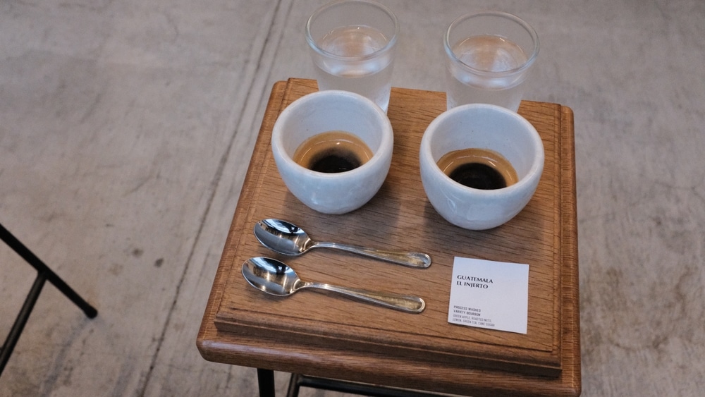 Tokyo Japan - March 26 2025: A specialty coffee tasting setup with two espresso cups, glasses of water, and a tasting card for Guatemala El Injerto, served in a minimalist cafe setting.