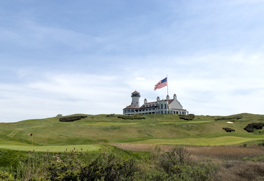 white building on green meadow grass hill next to american flag of the united states of america usa golf course next to hudson river bayonne new jersey