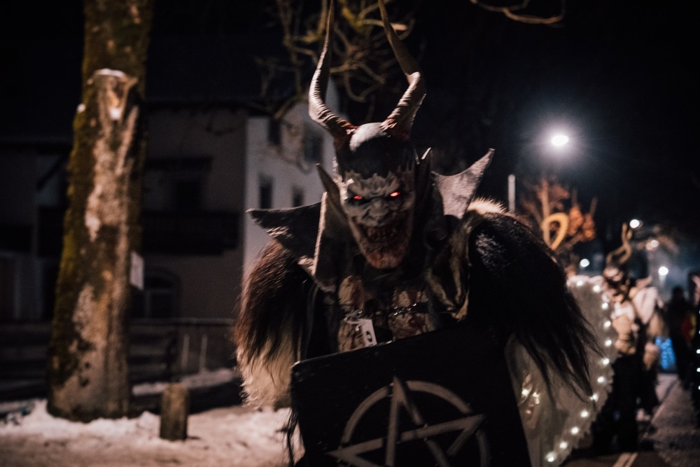 Austria. 29.11.2025: Krampus performers marching through a crowded street during a traditional Krampuslauf parade in Austria. the winter night. Alpine tradition held in early December