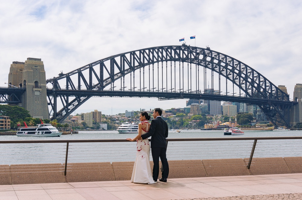 Sydney, Australia - October 10, 2014: Young Asian wedding couple of bride and groom posing against Sydney Harbour Bridge on the background