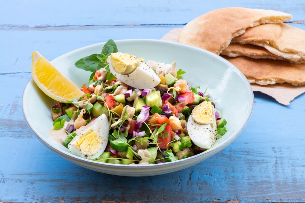 Jerusalem Salad - Flavor Dish Made From Tomato, Cucumber, Red Onion, and Parsley, Grilled Eggplant Cubes, Chickpeas Served With Hard Boiled Egg and Tahini Sauce