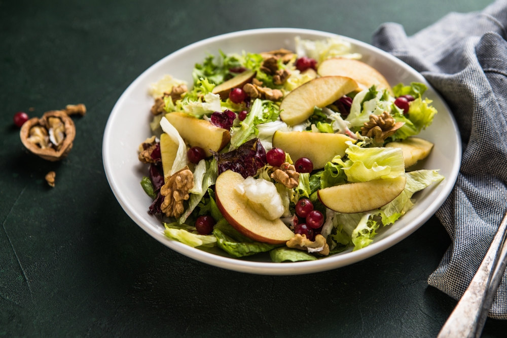 Fresh Waldorf salad with lettuce, green apples, walnuts and celery on wooden table. Top view.Copy space