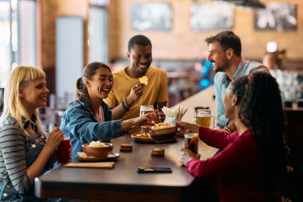 Young happy woman eating with friends in a pub.
