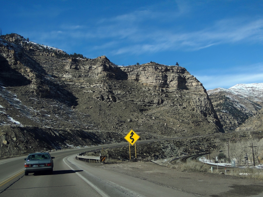 Driving through canyon under Book Cliffs sedimentary formations, along I-70 highway near Grand Junction, Colorado
