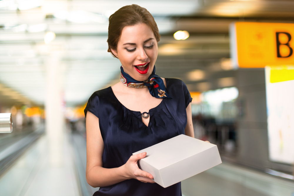 Pretty stewardess holding a box inside the airport