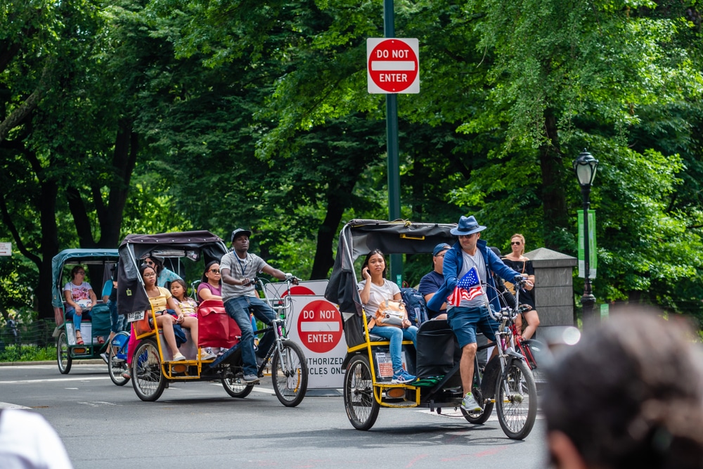 New York, USA - June 6, 2019: Passengers in the back of a pedicab look out as they pass near Central park.