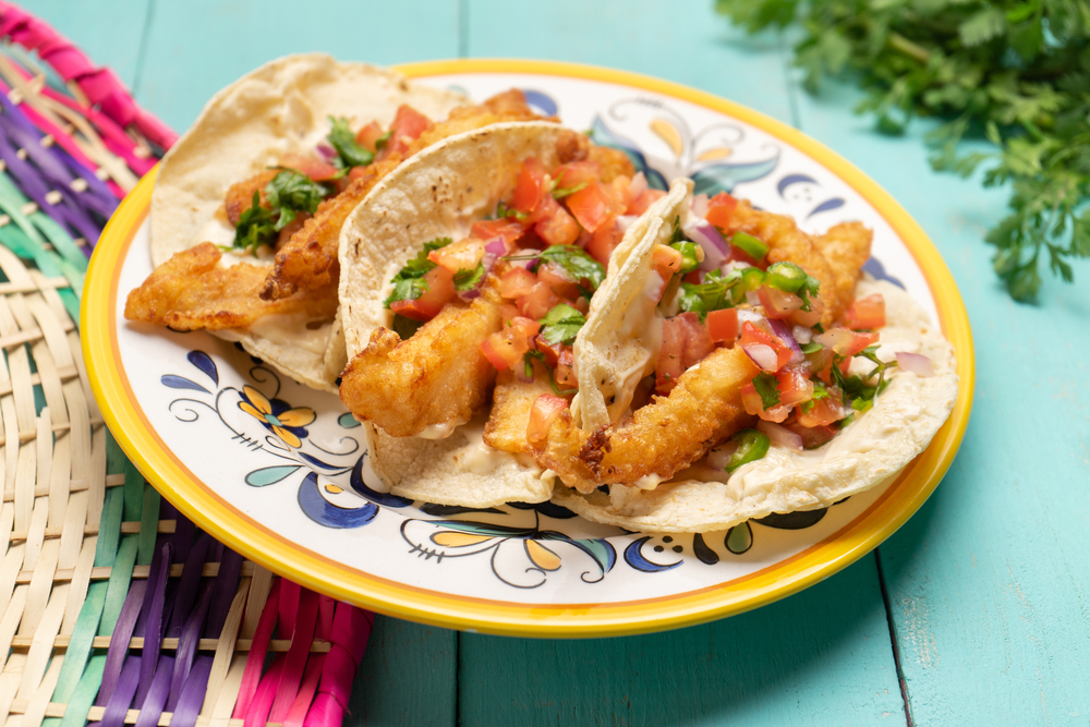 Traditional mexican breaded fish tacos also called ensenada on turquoise background