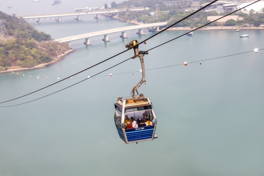 HONG KONG - FEBRUARY 26, 2024: Tourists in a Ngong Ping 360 cable car cabin traveling over the water at Lantau Island, Hong Kong.