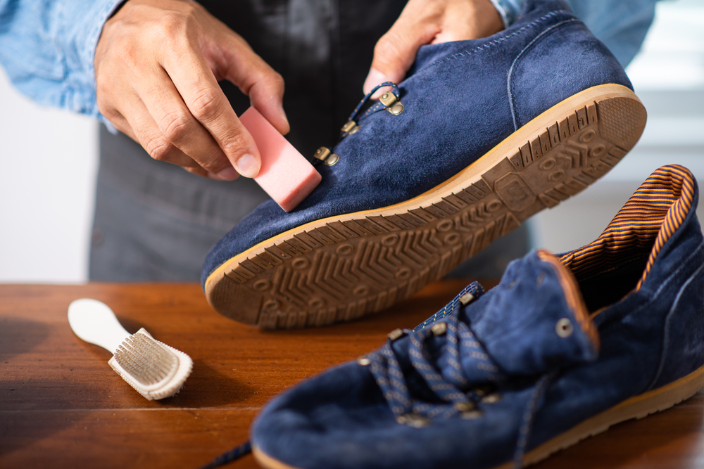 The man cleaning the blue suede shoes. Shoe care concept.